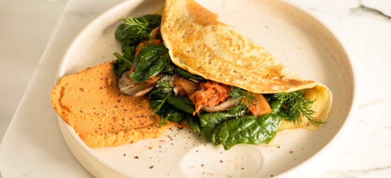 Omelette relleno de verduras frescas servido con puré de pimientos.